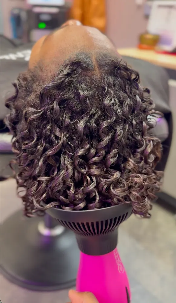 Defined dark curls with violet tones, held in a diffuser for an air-dried natural finish